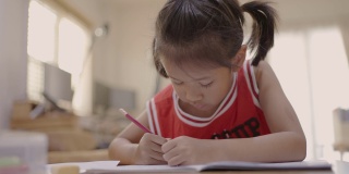 一个亚洲小女孩在家里学习写字
