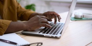 黑人在办公桌上用白色笔记本电脑工作，背景是办公室在家里的Spbas