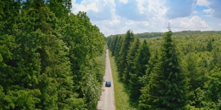 汽车行驶在令人惊叹的绿色自然的道路上。蓝色电动汽车在路上行驶。环保车在夏天行驶。
