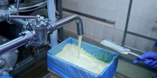液体黄油正从管子里倒进容器里。生产黄油的工厂。自动化的生产线。粮食生产。