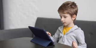 一个小男孩正在家里的平板电脑上玩游戏。