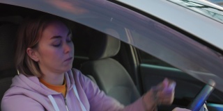 一名年轻的白人女子紧张地坐在右驾驶的驾驶座上，向警察提交文件。警笛灯在闪烁。交通违法罚款的概念
