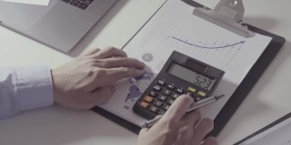 在现代的办公室里，商人们在桌子上处理关于成本的财务和计算器，还有手提电脑和手机