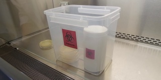 视频镜头特写，科学家检查了生物危害箱里的培养皿，准备在微生物实验室里存放危险液体和化学品。