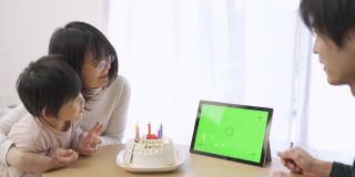 一个亚洲家庭在屏幕上庆祝他们的生日，蛋糕上用日语写着生日快乐