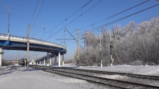 俄罗斯，莫斯科地区，2022年2月5日。电动客运列车从莫斯科的一座公路桥下驶出。冬天的阳光灿烂的日子视频素材模板下载