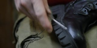 鞋匠的双手用锋利的锥子和黑色的线缝合