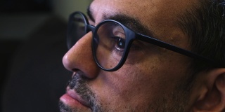 一个大胡子男人的特写镜头，他戴着眼镜，看着电脑显示器，读出眼睛的移动