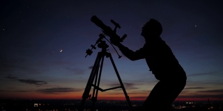 一个男人用天文望远镜观察星空的剪影。