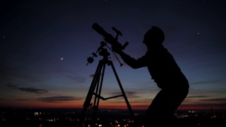 一个男人用天文望远镜观察星空的剪影。视频素材模板下载