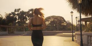 日落时分，身着运动服的女子在城市里慢跑锻炼。