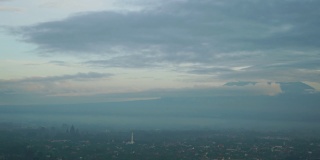 美丽的时间推移镜头日惹市在雾蒙蒙的早晨移动的云和默拉皮山的背景。拍摄分辨率为4k
