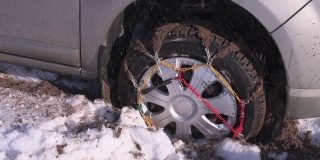 装有链条的车轮陷在雪和泥里，不停地旋转。