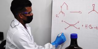化学家在实验室里向一个同事解释黑板上的实验。
