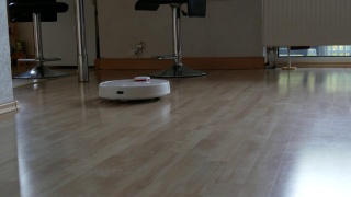 白色智能吸尘器清扫家里的油毡地板。现代科技使生活更容易视频素材模板下载