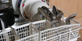 近距离观察清洁和闪亮的勺子和叉子在一个开放的洗碗机