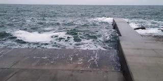 巨浪冲击防波堤。混凝土防波堤风暴和白色泡沫海浪。自然背景。暴风雨天气。自然现象