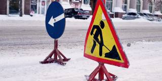 吹雪机清除结冰的冬季道路。扫雪机清除城市街道上的积雪。警告路标。冬季服务车辆吹雪机工作。清理积雪结冰的道路。