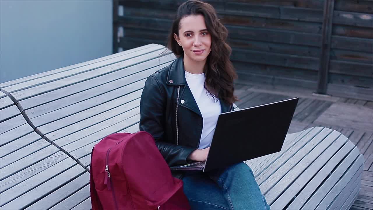一个在外面带着笔记本电脑的年轻女人