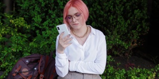 一头粉红色头发的年轻女子使用智能手机