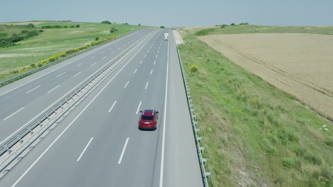航拍，慢镜头红色四驱车行驶在空无一人的高速公路上。