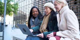 西班牙裔，亚裔和白人商业女性在户外商务会议使用笔记本电脑