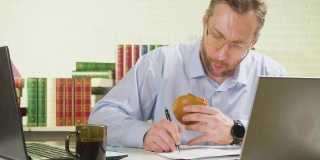40岁的男人在办公室里努力工作，吃着不健康的食物——有截止日期的观念