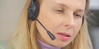 呼叫中心女话务员戴着耳机与客户通话。视频肖像在线它支持专家与客户在线交谈。自由职业女性，戴耳机和麦克风