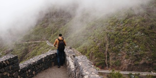 年轻的旅行者站在悬崖边，观察山上的雾