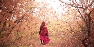 接下来的镜头是一位红发女士在秋天的森林里走在金黄色的树林里，童话般的风格