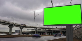 高速公路附近有绿色的大型广告牌。汽车、云、间隔拍摄。