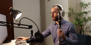 年轻的企业家在家里吹单簧管，用电脑录制音乐并在线播放