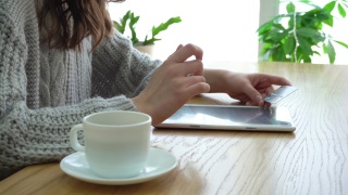 女孩拿着信用卡，坐在咖啡馆里用平板电脑视频素材模板下载