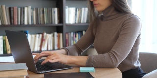 大学生使用笔记本电脑观看在线远程学习，研讨会，远程大学网络研讨会，或在大学的创意空间进行虚拟课堂会议。这个女孩在图书馆用笔记本电脑工作