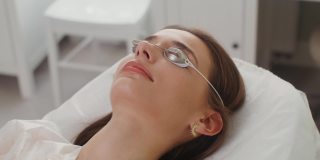 一位戴着防护眼镜的女病人躺在美容院的房间里
