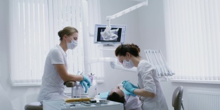 一位女牙医正在检查躺在牙科椅上的病人的口腔