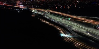 夜晚，城市道路上的汽车驾驶鸟瞰。现代化摩天大楼的夜间城市景观。宏伟的城市景观，霓虹灯照明与交通高速公路。电影汽车风景