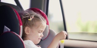小女孩在坐汽车座椅时喜欢吹肥皂泡