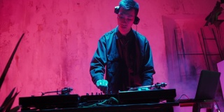 Asian Appearance的现代DJ在霓虹灯下演奏音乐。