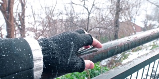外面下雪时，一个男人的手指在旧铁栅栏上移动
