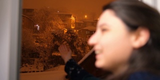 不集中的快乐女人看着下雪的夜晚的时间