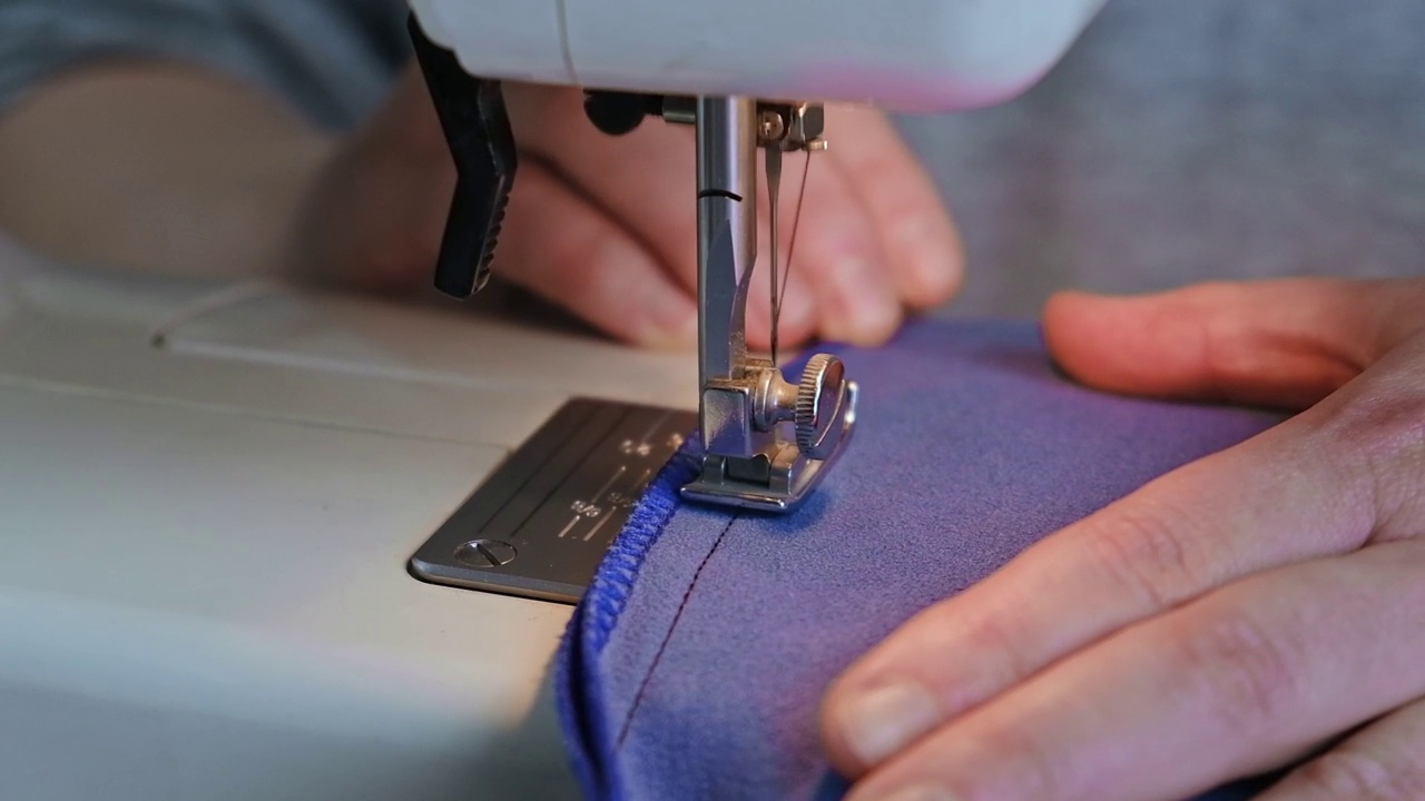 女裁缝在电动缝纫机上缝衣服