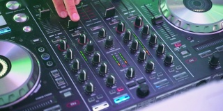 特写的DJ的双手扭动着，按下DJ遥控器上不同的按钮，颜色和轻音乐在俱乐部里。与dj派对