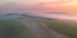 无人机在清晨浓雾笼罩的农田上空飞行。