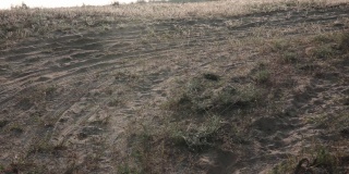 越野车在中场，摄像机向右移动。草原沙地上的轮胎印。自然视频背景，景观