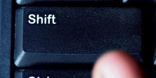 人体手指按下电脑键盘上的shift键的特写