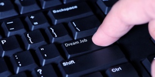 人的手指在电脑键盘上按下梦想工作的键。理想职业的概念