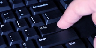 人类手指按下电脑键盘上的帮助按钮的视频片段
