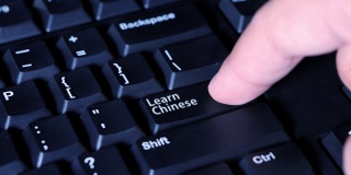 视频画面显示，男性手指按下了电脑键盘上的“学习中文”按钮