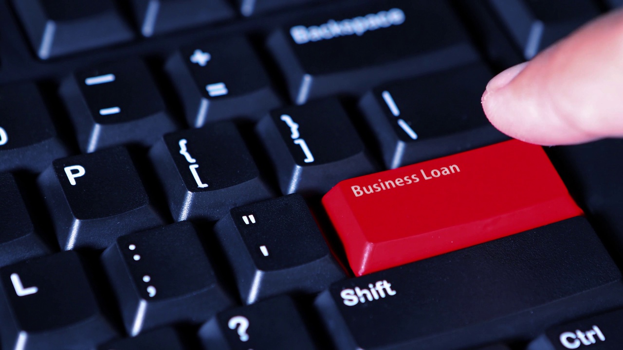 一个男性手指按下电脑键盘上的红色商业贷款按钮的微缩视频片段